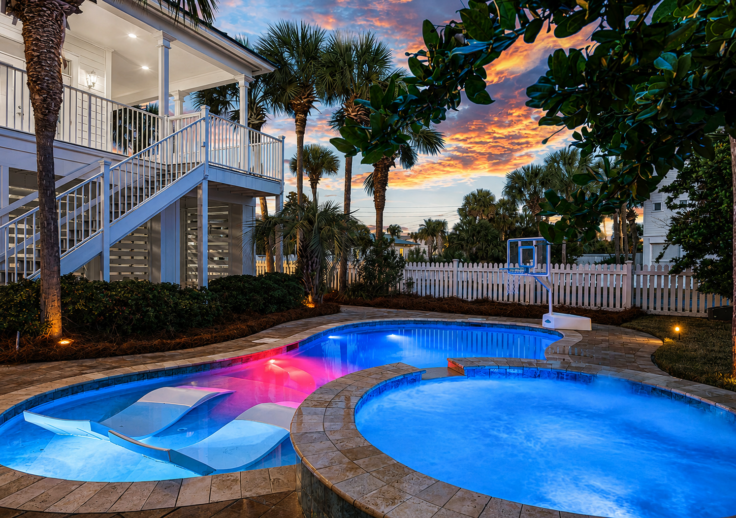 Private heated pool and hot tub glowing at sunset behind this Destin beach house with pool